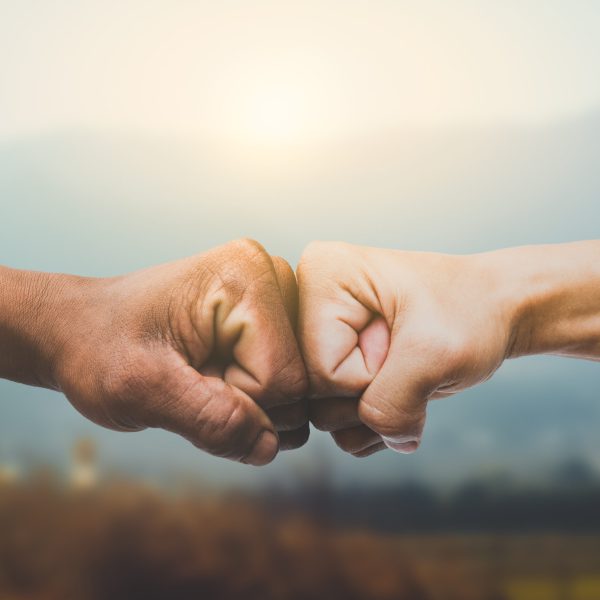Man giving fist bump in sun rising nature background. power of t Man giving fist bump in sun rising nature background. power of teamwork concept. vintage tone