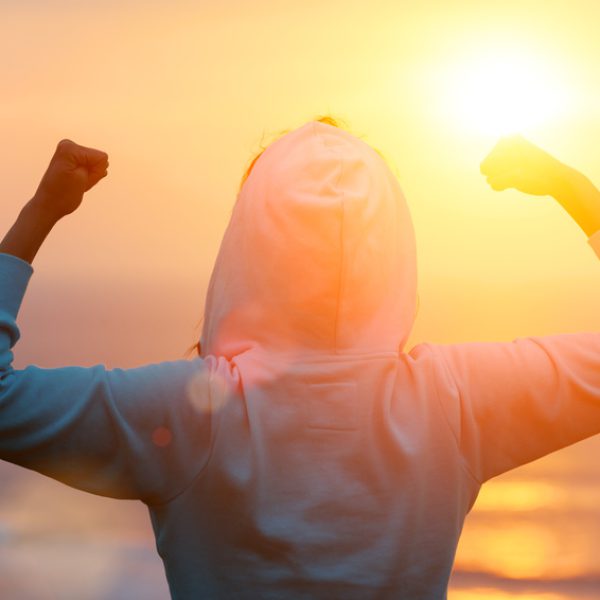 Back view of strong motivated woman celebrating workout goals towards the sun. Morning healthy training success. Back view of strong motivated woman celebrating workout goals towards the sun. Morning healthy training success.
